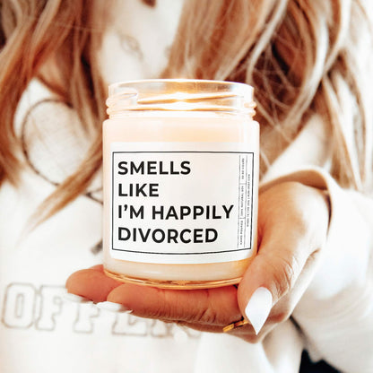 Smells Like I'm Happily Divorced 9oz Candle. The text is printed with big bold words. Held by a model.